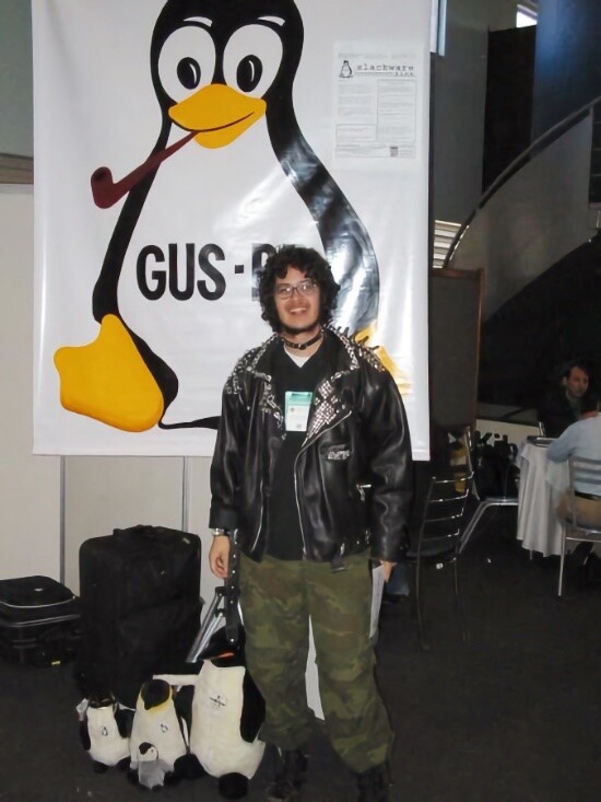 Piter Punk em frente ao banner do grupo de usuários de Slackware no FISL de 2004