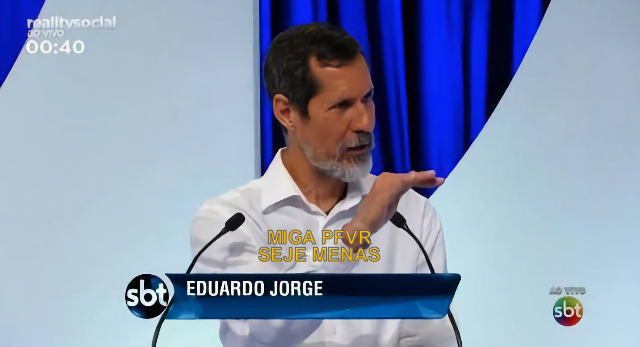Eduardo Jorge em programa do SBT, gesticulando com a mão espalmada para baixo, e a legenda “Miga pfvr seje menas“