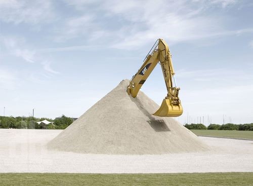 um braço de escavadeira se projetando de um monte de areia que a soterra