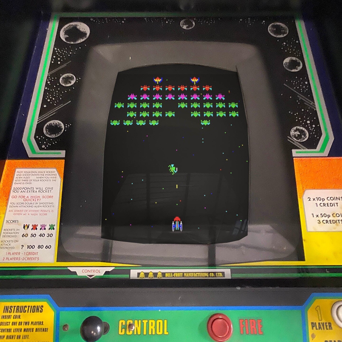 Tela do Galaxian em máquina de fliperama, com uma nave inimiga saindo de formação para atacar a nave do jogador