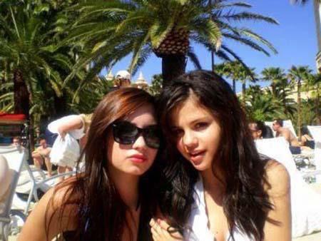Foto de Selena GOmez e Demi Lovato, do ombro para cima, em ambiente de piscina de hotel, nos anos 10