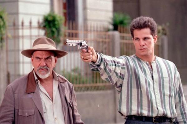 Ao lado do Major Bentes, o protagonista Flamel empunha uma arma de fogo, usando uma camisa com a gola flamel.