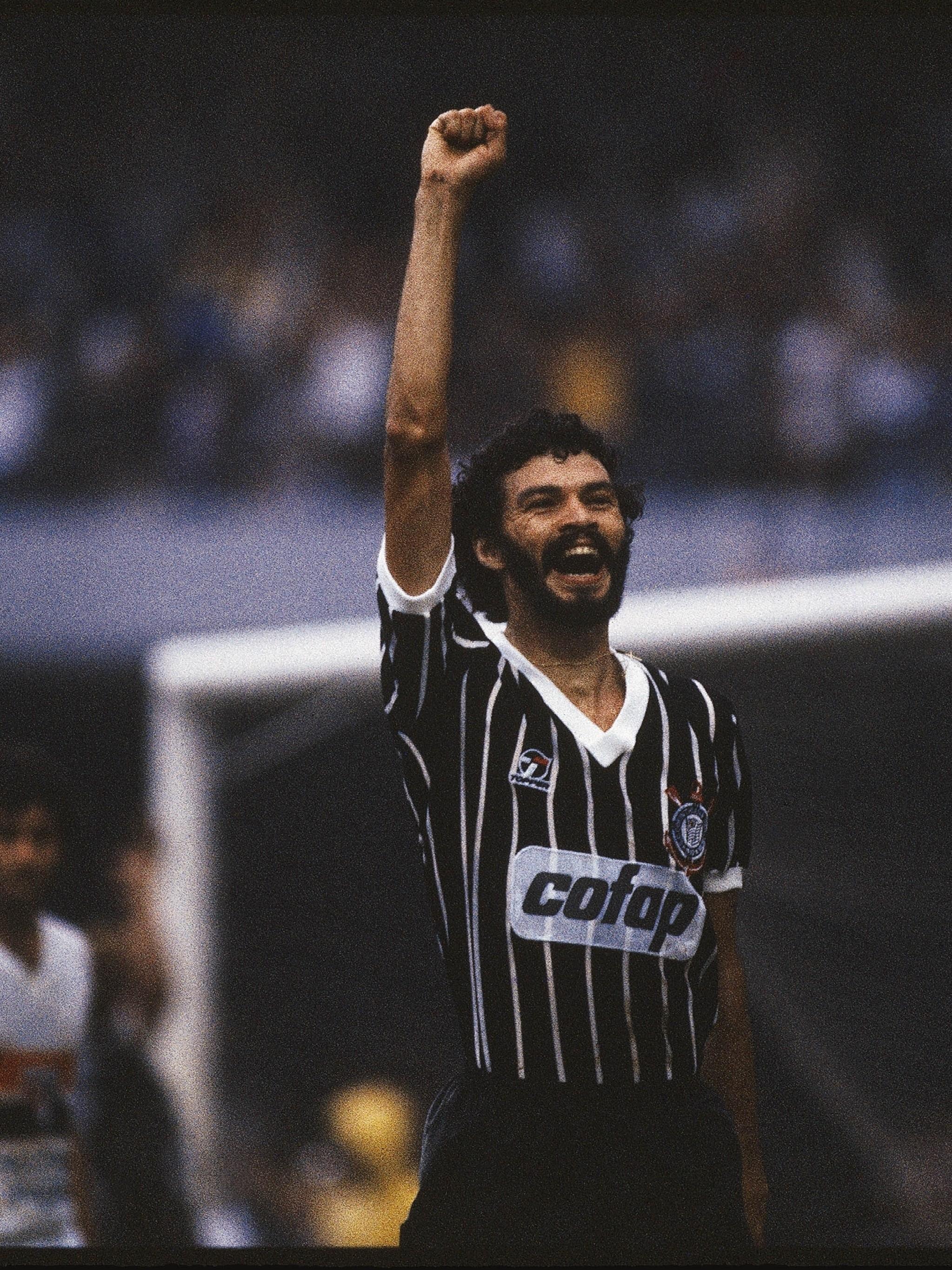 Sócrates comemora em campo, com a camisa do Corinthians, braço erguido e punho cerrado