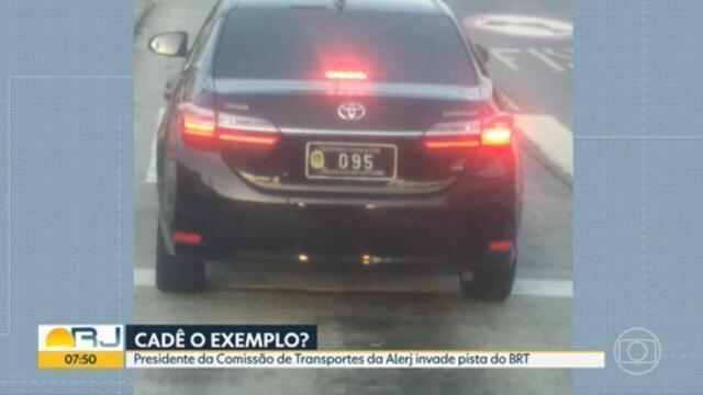 Foto jornalística de um carro oficial do poder Legislativo do RJ, com a legenda: CADÊ O EXEMPLO? Presidente da Comissão de Transportes da Alerj invade pista do BRT.
