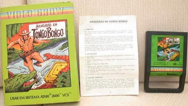 Foto da caixa, manual e cartucho de “Aventuras em Tongo Bongo“, ilustradas por um aventureiro de chapéu, botas e coldre, defrontado por um crocodilo e uma serpente.