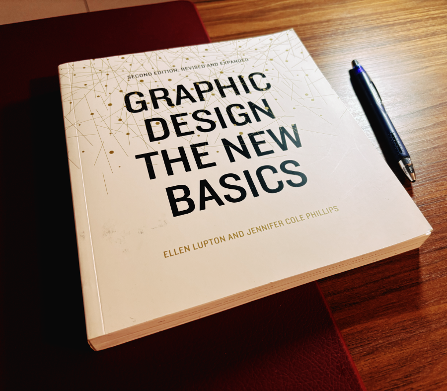 Meu exemplar do livro Graphic Design The New Basics, cuja capa é branca, decorada com grafismos e tendo como protagonista visual o título, em letras grandes e de alto contraste com o fundo. O livro foi fotografado ao lado de uma caneta azul.