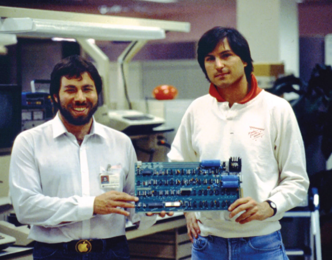 Foto de 1976 com Steve Wozniak e Steve Jobs posando com uma placa do microcomputador Apple I.