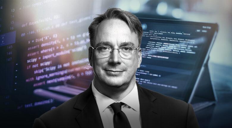 Foto em preto e branco de Linus Torvalds, de paletó e gravata, em frente a telas exibindo código.