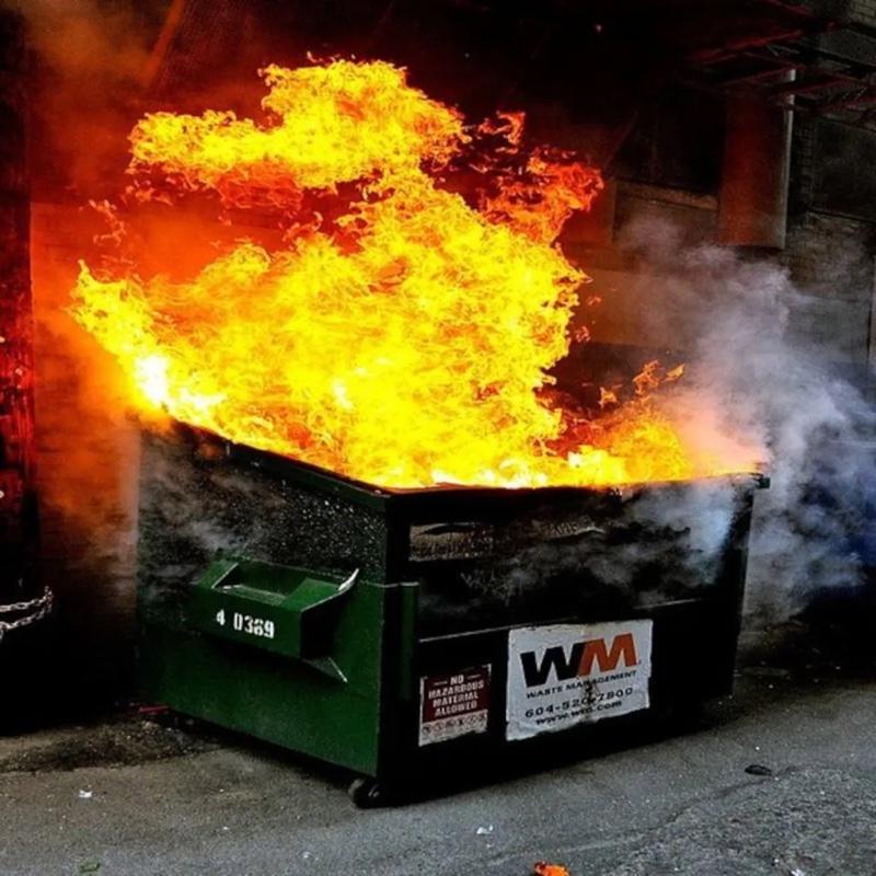 Foto de um container de lixo, em chamas.