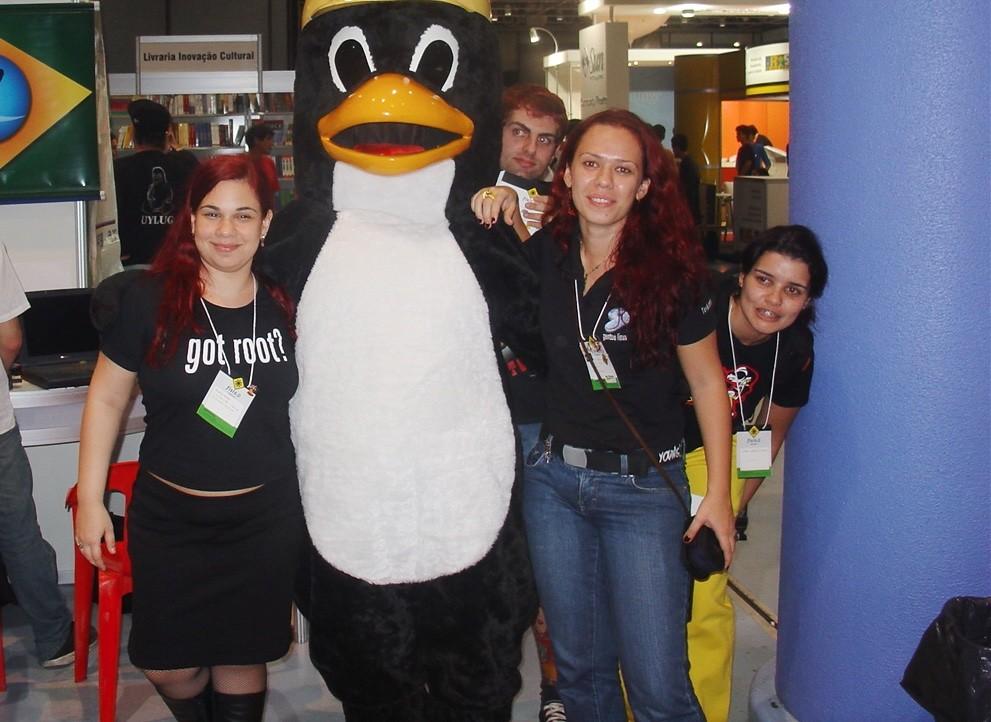 Integrantes das LinuxChix em um FISL, posando com o mascote Tux.<br>